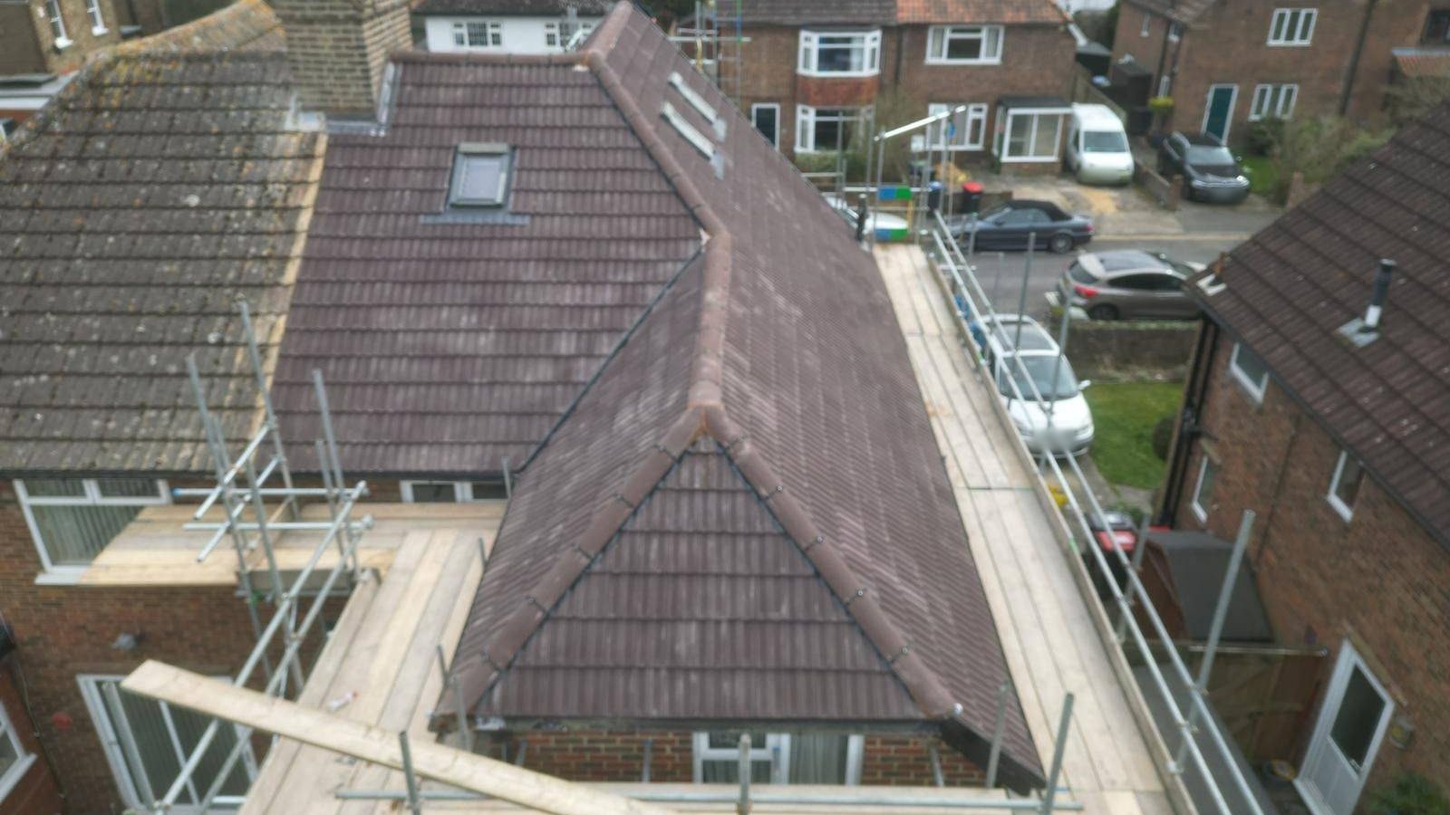 A hipped roof in Canterbury freshly re-tiled by StoneRidge Roofing, seen from the scaffold with the neighbouring streets behind