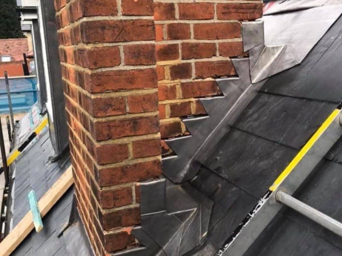 Brick chimney with new stepped flashing on a slate roof by StoneRidge Roofing