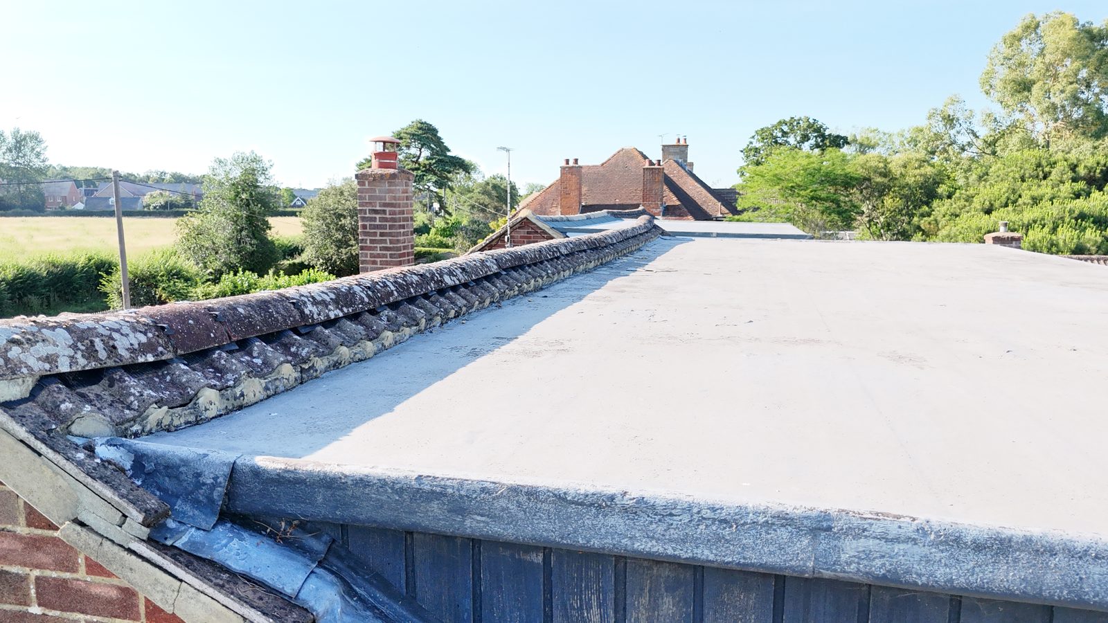 A flat roof completed by StoneRidge Roofing, with lead flashing where it meets the tiled roof