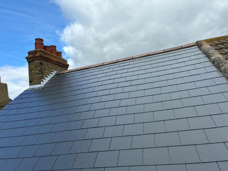 Finished slate roof beside a brick chimney stack by StoneRidge Roofing
